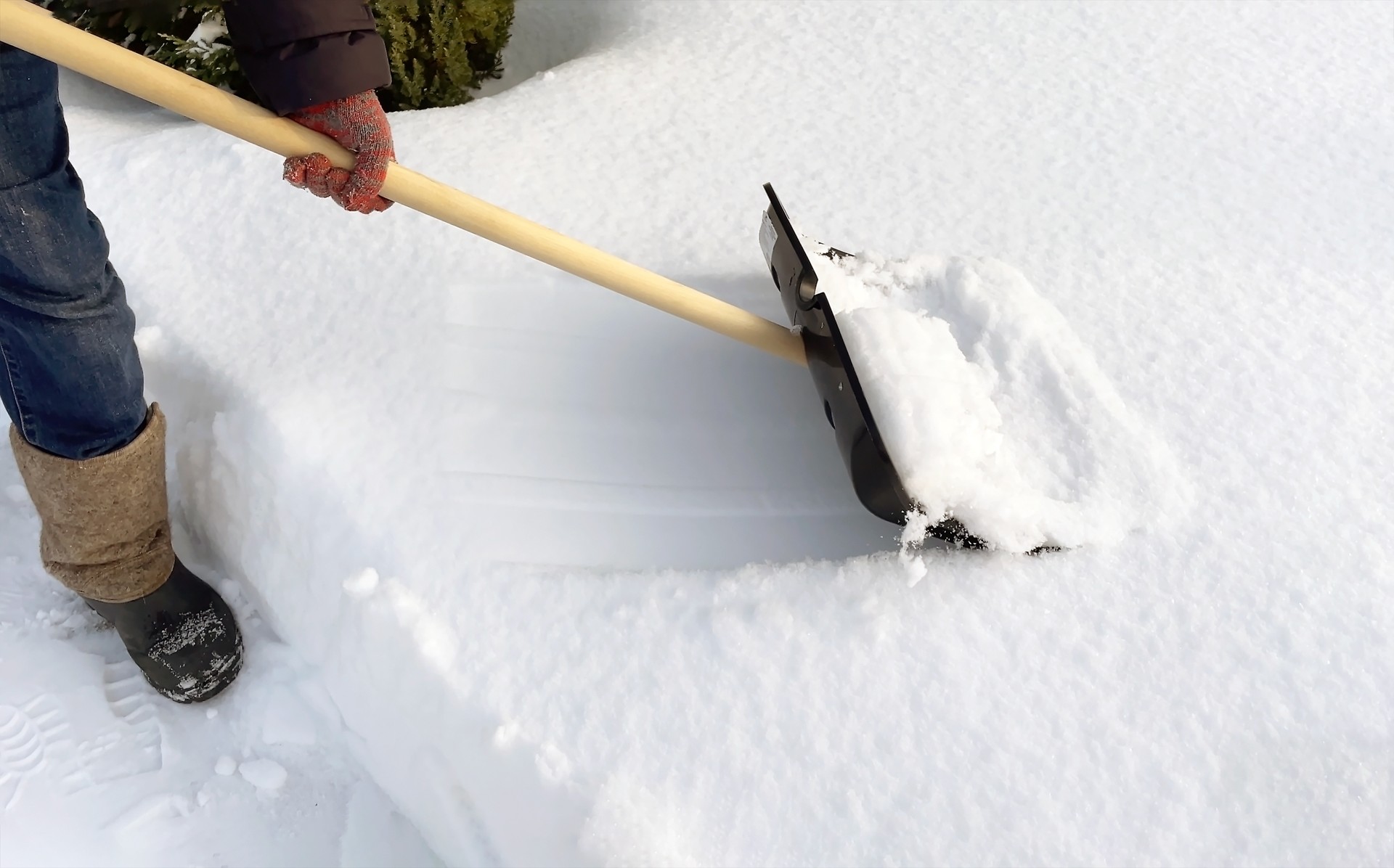 A man cleans the path from snow with a shovel. Snow removal